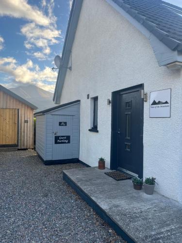 a white house with two garage doors on it at View of the Mountain in North Ballachulish