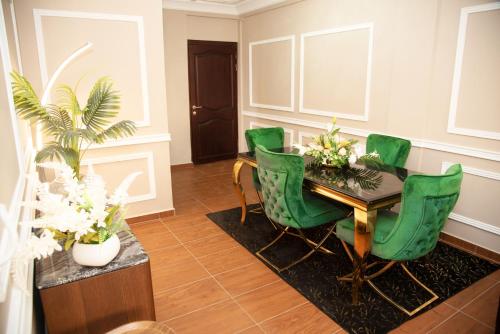 a dining room with a table and green chairs at Résidence Le Sommet - Appartement VIP in Douala
