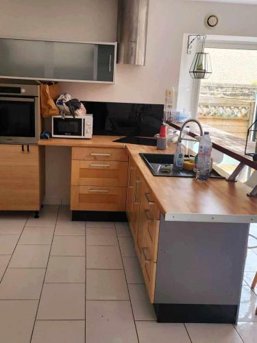 a kitchen with a sink and a microwave at Maison près de la mer , les plages du débarquement in Courseulles-sur-Mer
