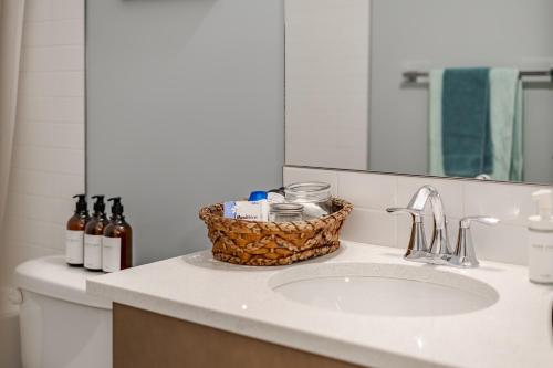 a bathroom with a sink with a basket on it at Luxe Suite close to Spruce Meadows in Priddis