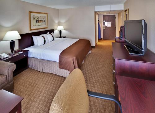 a hotel room with a bed and a flat screen tv at Ramada by Wyndham Midtown Grand Island in Grand Island