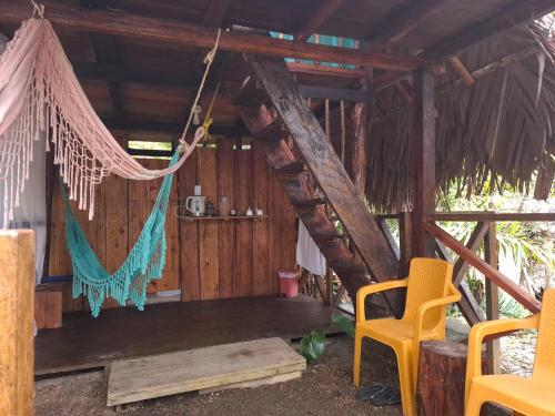 a wooden cabin with a hammock and two chairs at Mangle House Cabañas Ladrilleros in Buenaventura