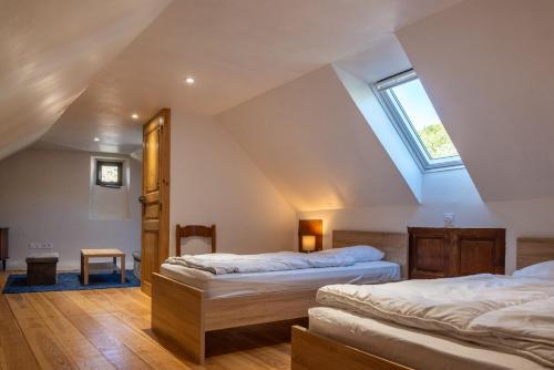 une chambre mansardée avec deux lits et une lucarne dans l'établissement Maison almir, à Le Pont-de-Montvert