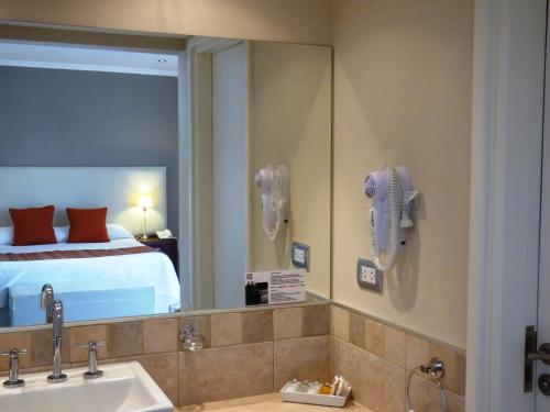 a bathroom with a sink and a mirror and a bed at Villa Nuccia Hotel Boutique in Mar del Plata