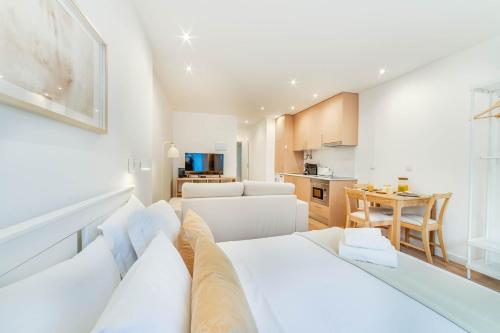 a living room with a white couch and a kitchen at Blue Charm - Campolide Apartments in Lisbon