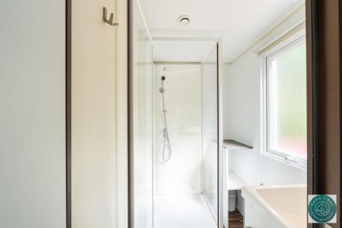 une salle de bain blanche avec une douche et un lavabo dans l'établissement Petit cocon ensoleillé, le mobil-home Alélé, à Bias