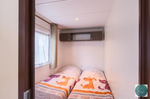 - un canapé dans une petite chambre avec fenêtre dans l'établissement Petit cocon ensoleillé, le mobil-home Alélé, à Bias