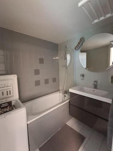 La salle de bains blanche est pourvue d'un lavabo, d'une baignoire et d'une douche. dans l'établissement Appartement Coeur de Granit Rose, à Perros-Guirec