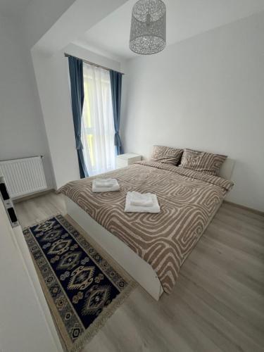 a bedroom with a large bed with two towels on it at Blue Apartment in Floreşti