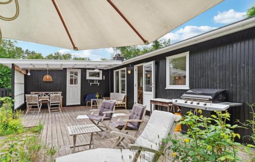 an outdoor patio with chairs and an umbrella at 4 Bedroom Cozy Home In Vejby in Vejby