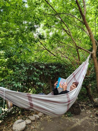a woman laying in a hammock reading a book at Andamundos Hostel in Mina Clavero