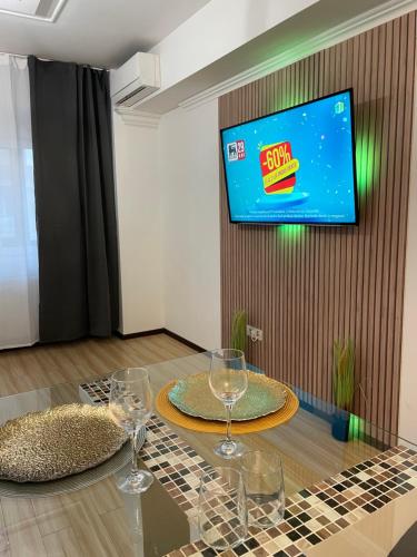 a table with wine glasses and a tv on a wall at MilitariResidence Luxury 54 in Roşu