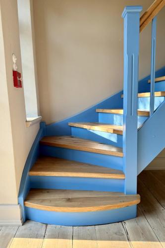 a blue staircase with wooden steps in a room at Gesamtes Historisches Kapitänshaus in Fehmarn