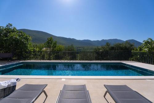 a swimming pool with two chairs and a fence at New!Villa Giro in Slime