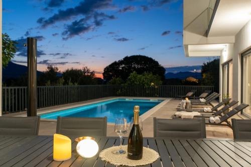 a bottle of wine on a table next to a swimming pool at New!Villa Giro in Slime