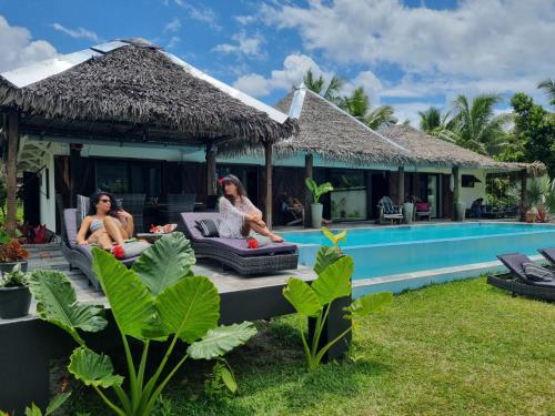 two women sitting on the deck of a house with a swimming pool at La VILLA BORAHA 300m2 PROPRIÉTÉ ENTIERE en bord de plage PISCINE PRIVEE Cuisine TV Wifi in Sainte Marie