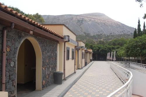 a street with a building and a mountain in the background at Hotel Al Togo Fitness & Relax in Vulcano