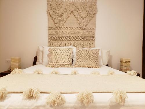 une chambre avec un grand lit avec des draps et des oreillers blancs dans l'établissement Ipana Condos by HA, à Playa del Carmen