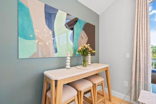 a dining room table with stools and a vase of flowers at Beach Rd, 300ft to Beach Access & 500ft to Siesta Key Village, 2bdr in Siesta Key