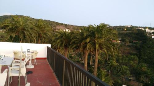 a balcony with palm trees and a table and chairs at Pensión Amparo Las Hayas in Valle Gran Rey