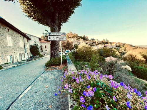 un panneau de rue sur le côté d'une route avec des fleurs dans l'établissement Kaki Green Appartement Lumineux, Chic & Cosy WIFI Centre ville, à Chalencon