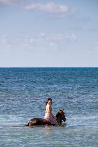 a woman riding a horse in the ocean at Monasterio del Viento in Bahia Maracaibo