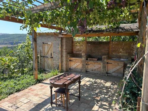 an outdoor kitchen with a wooden table and a grill at მყუდრო სახლი ფუნიკულიორის პარკთან in Okrokana