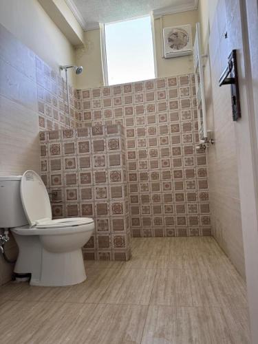 ein Badezimmer mit Toilette und Dusche mit Fenster in der Unterkunft Serenity Suites in Bhurban