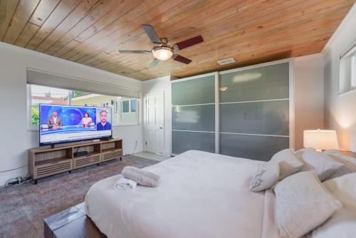 a bedroom with a large bed and a flat screen tv at Charming House with Private Pool n Coral Gable in Miami
