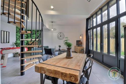 une salle à manger avec une table en bois et un escalier en colimaçon dans l'établissement La grange aux portes des ecluses, à Bazouges-sous-Hédé