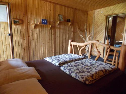 een kamer met een bed en een houten muur bij Guest House Kalniņi in Kārļi