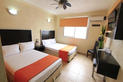 a hotel room with two beds and a television at Hotel Estadio in Guadalajara