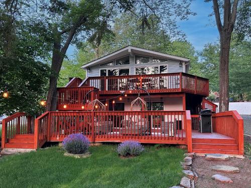 a house with a large deck with a balcony at Majestic Lake Front Chalet in Tobyhanna