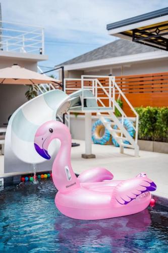 a pink swan float in a pool with a slide at come home pool villa cha-am in Phetchaburi