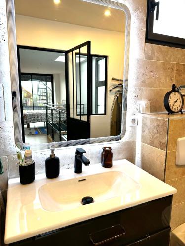 une salle de bain avec un lavabo et un grand miroir dans l'établissement Libre Pensée, à Romainville
