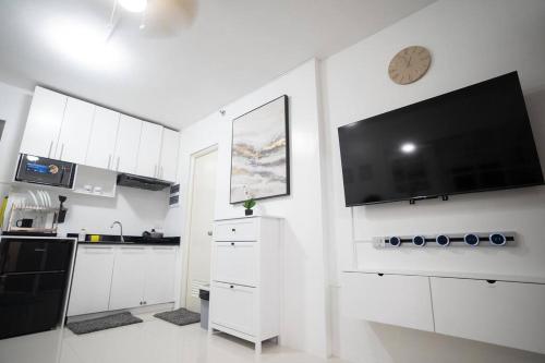 a white kitchen with a flat screen tv on the wall at Palawan Cozy 2BR w Washer, Dryer, Gym, Pool for 6 in Puerto Princesa City