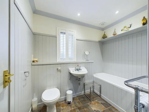 a white bathroom with a toilet and a sink at Rokeby in Bamburgh