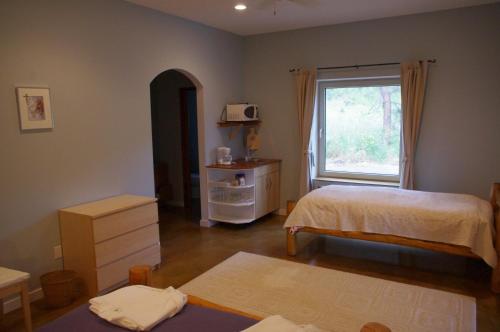 a bedroom with two beds and a window with a microwave at Baergnaescht B&B in Osoyoos