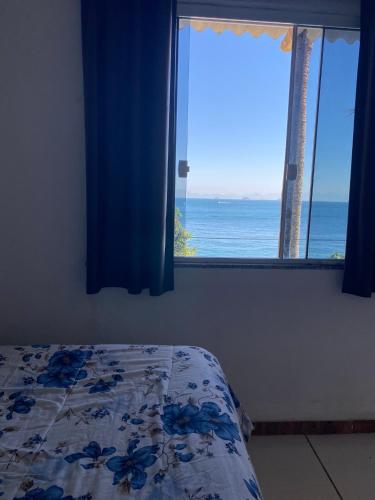a bedroom with a window with a view of the ocean at SUÍTES PÉ na AREIA ANGRA in Angra dos Reis