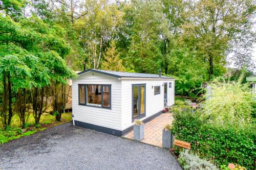 a small white tiny house in a garden at Bos Chalet Natura - Rust en Natuur op de Veluwe Putten in Putten