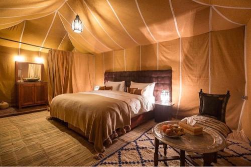 a bedroom with a bed and a table in a tent at desert tribe luxury camp in Merzouga