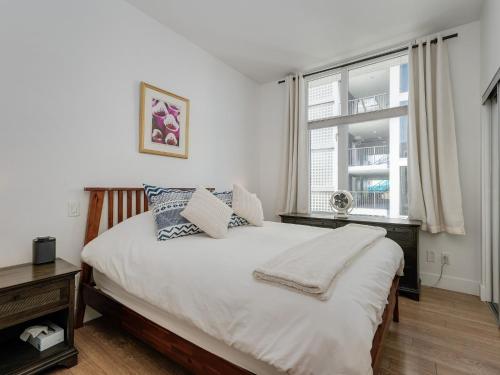 a bedroom with a large white bed with a window at The Bohemian, min 30-Day Stay with Breathtaking Views and Home Office by Victoria Prime! in Victoria