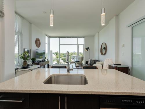 a kitchen with a sink and a living room at The Bohemian, min 30-Day Stay with Breathtaking Views and Home Office by Victoria Prime! in Victoria