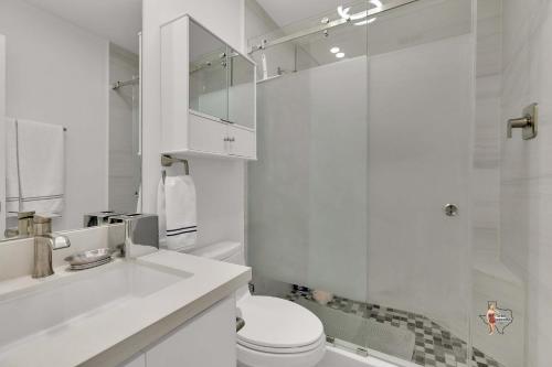 a white bathroom with a toilet and a shower at Bahia Mar Solare Beachfront Resort Condos with Two Pools in South Padre Island