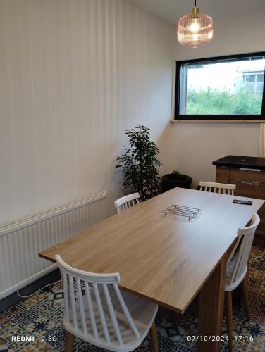 a wooden table with white chairs in a room at Gite de la salamandre in Pléguien