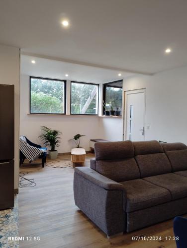 a living room with a couch and some windows at Gite de la salamandre in Pléguien
