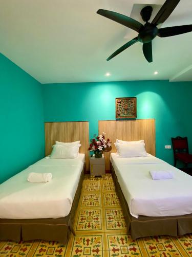 two beds in a room with a ceiling fan at Bayu Bayu Hotel by Soft Loft in Tanjung Bungah