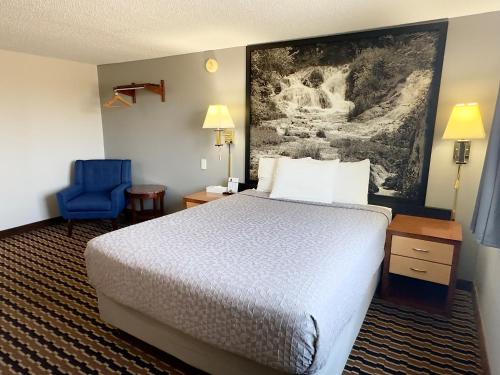 a hotel room with a bed and a blue chair at Yankton Inn in Yankton