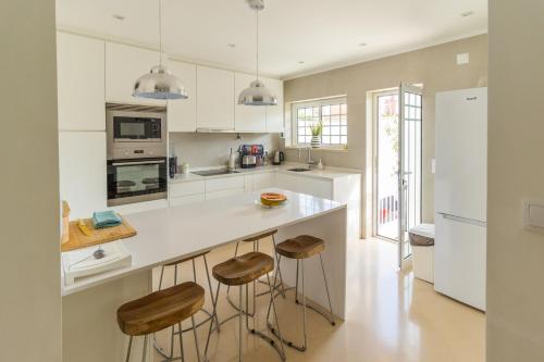 a kitchen with a white counter and stools at Villa Penedo in São Domingos de Rana