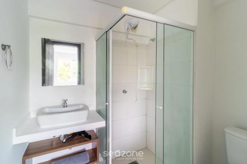 a bathroom with a sink and a glass shower at SPT - Studios Convenientes em Blumenau/SC in Blumenau